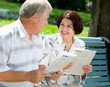 Happy senior couple reading outdoors