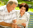 Happy senior couple reading outdoors