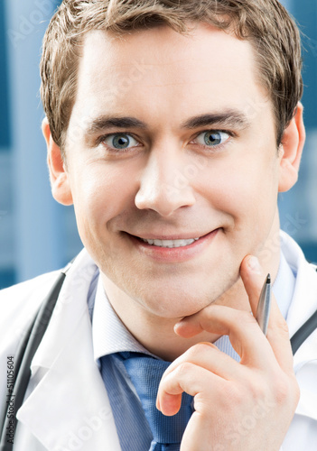 Photo: Happy smiling young doctor at office Happy smiling young doctor at office