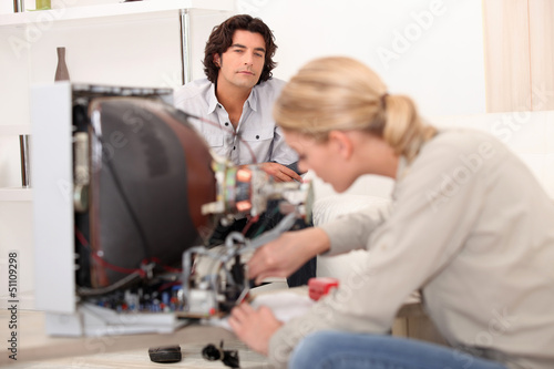 Photo: Woman repairing a television set Woman repairing a television set