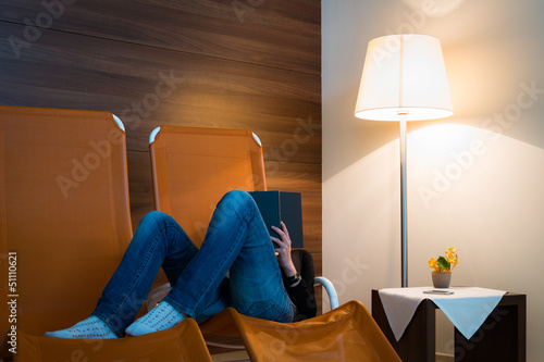 Photo: girl reads book lying in lounger with lamp front of wooden wall girl reads book lying in lounger with lamp front of wooden wall