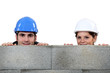 male bricklayer and female counterpart hiding behind wall
