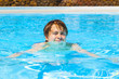 cute handsome teenage boy swims in the pool