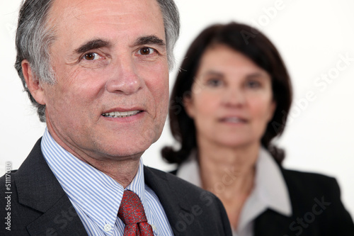 Photo: Older businessman with a woman in the background Older businessman with a woman in the background