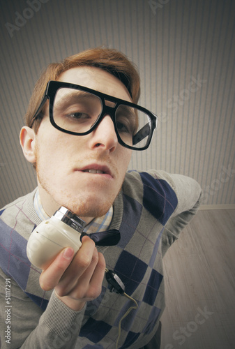 Photo: Nerd student shaving with vintage electric shaver Nerd student shaving with vintage electric shaver