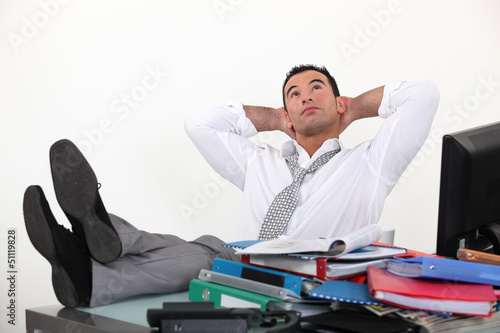 Photo: Businessman reclining in his chair despite being overworked Businessman reclining in his chair despite being overworked