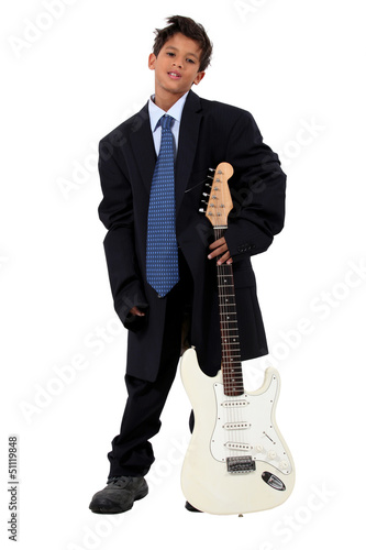 Photo: Boy in loose fitting suit stood with electric guitar Boy in loose fitting suit stood with electric guitar
