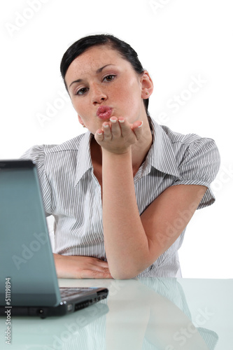 Photo: Woman at desk blowing kiss Woman at desk blowing kiss
