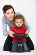 a mother and her son playing with a steering wheel