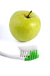 Toothbrush with toothpaste and green apple isolated over white