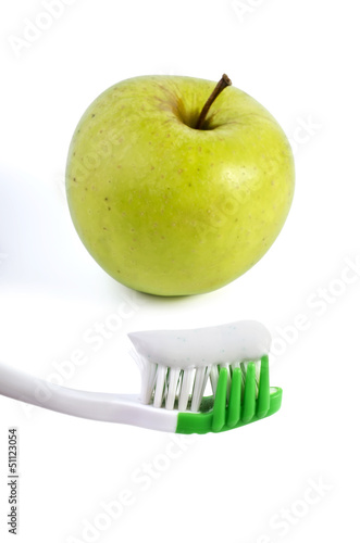 Photo: Toothbrush with toothpaste and green apple isolated over white Toothbrush with toothpaste and green apple isolated over white