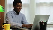 Man typing at a laptop then laughs and continues typing