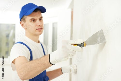 Photo: Plasterer with putty knife at wall filling Plasterer with putty knife at wall filling