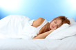 young beautiful woman sleeping on bed on blue background