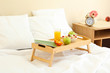 wooden tray with light breakfast on bed