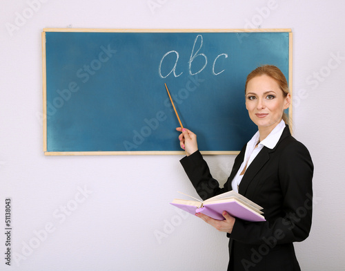 Photo: Portrait of teacher woman near chalkboard in classroom Portrait of teacher woman near chalkboard in classroom