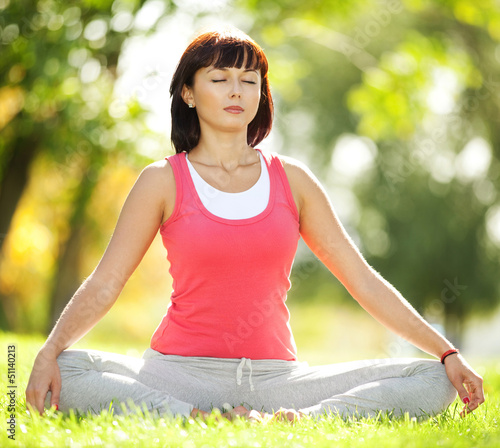 Photo: Pretty woman doing yoga exercises in the park Pretty woman doing yoga exercises in the park