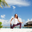 Photo: Pretty woman doing yoga exercises on the beach Pretty woman doing yoga exercises on the beach