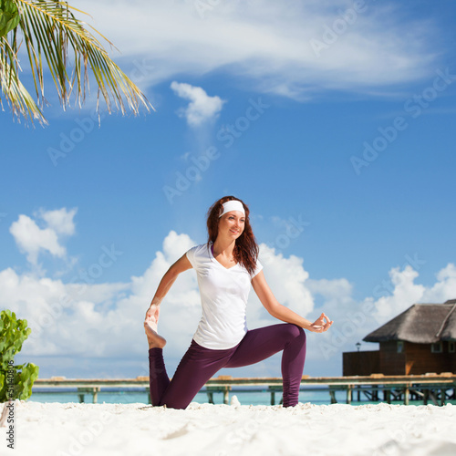 Photo: Pretty woman doing yoga exercises on the beach Pretty woman doing yoga exercises on the beach