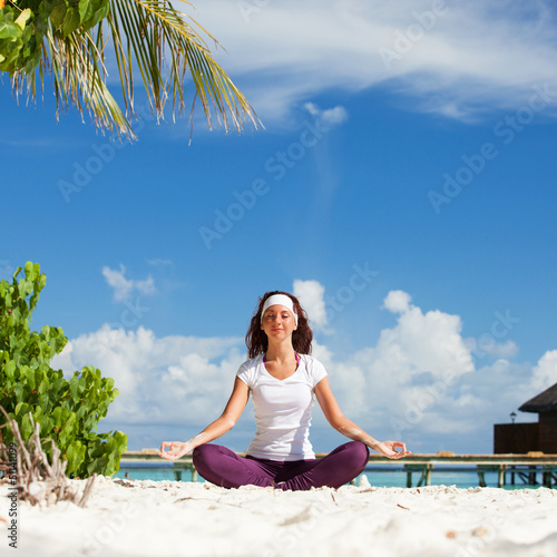 Photo: Pretty woman doing yoga exercises on the tropical beach Pretty woman doing yoga exercises on the tropical beach