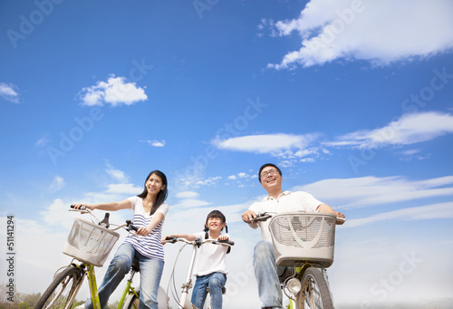 Photo: happy family riding bicycle with cloud background happy family riding bicycle with cloud background