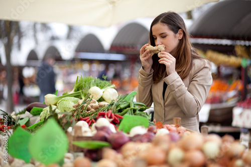 Photo: Young woman smelling ginger at the market Young woman smelling ginger at the market