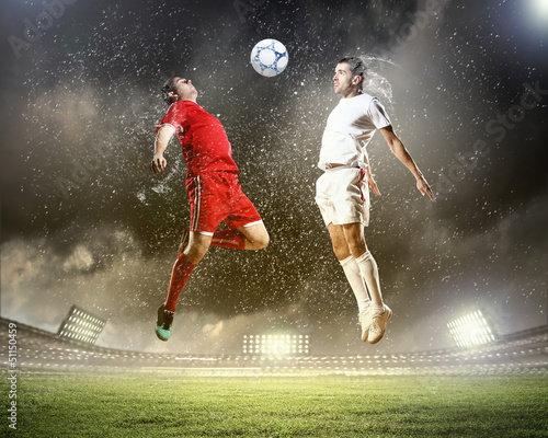 Photo: two football players striking the ball two football players striking the ball