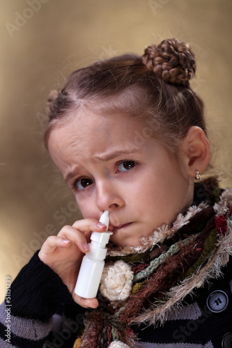 Photo: Young girl using nasal spray Young girl using nasal spray