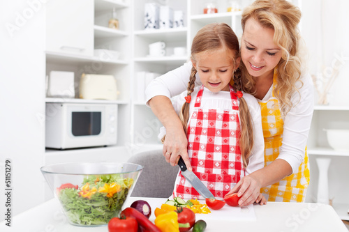 Photo: Woman and little girl preparing a vegetables salad Woman and little girl preparing a vegetables salad