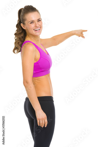 Photo: Smiling fitness young woman pointing on copy space Smiling fitness young woman pointing on copy space