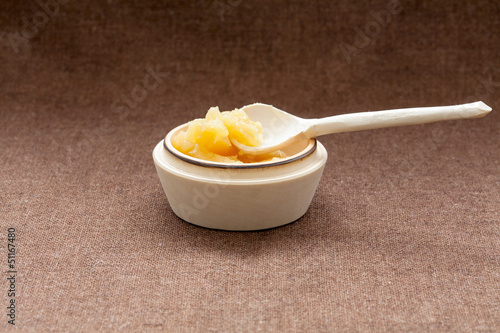 Photo: Pot of honey and wooden dipper on a cloth Pot of honey and wooden dipper on a cloth