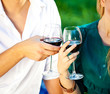 Photo: couple holding a glass of red wine in the garden couple holding a glass of red wine in the garden