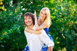 Photo: young couple having fun piggybacking in park young couple having fun piggybacking in park