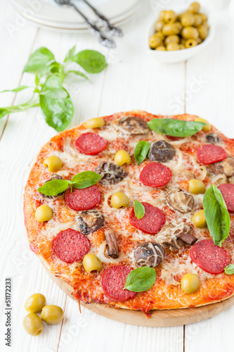 Photo: round pizza with slices of salami on white boards round pizza with slices of salami on white boards