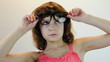 child plays with glasses and makes faces