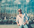 Happy middle-aged man in shirt against yacht port