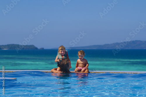 Photo: young happy mother and children enjoying vacation in swimming po young happy mother and children enjoying vacation in swimming po