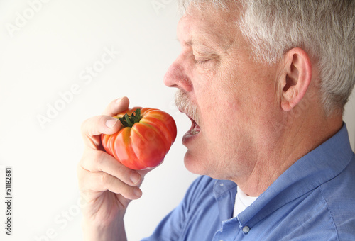 Photo: senior man eating big tomato senior man eating big tomato