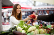 Farmer passing young woman a red pepper at the market