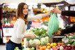 Young woman paying for vegetables at the market