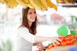 Cheerful young woman picking mandarine oranges at the market
