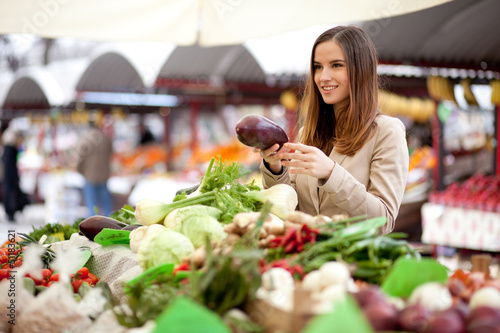 Photo: Young woman buying vegetables at the market Young woman buying vegetables at the market
