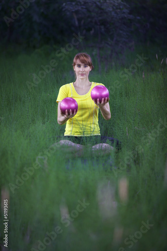 Photo: woman in yoga position, raising silver fitness balls woman in yoga position, raising silver fitness balls