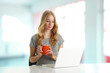 Young woman browsing on laptop and drinking coffee