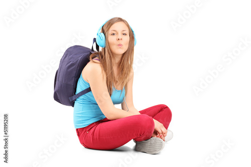 Photo: A schoolgirl with speakerphones sitting on a floor and giving ki A schoolgirl with speakerphones sitting on a floor and giving ki