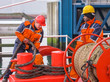 European deck officer working with ropes together with African s