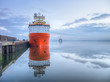Orange supply vessel in a port with oil rig
