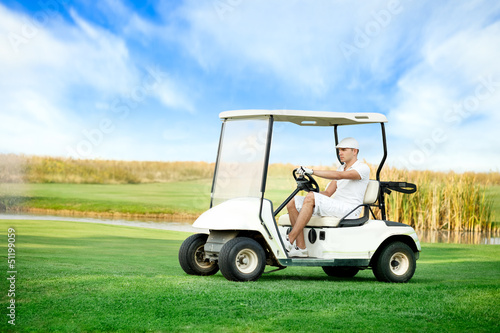 Photo: Young man driving golf buggy Young man driving golf buggy
