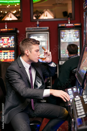 Photo: handsome man playing the slot machine handsome man playing the slot machine