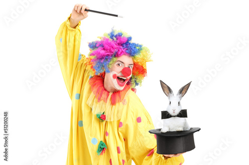 Photo: A circus clown performing a magic trick with a top hat and a rab A circus clown performing a magic trick with a top hat and a rab